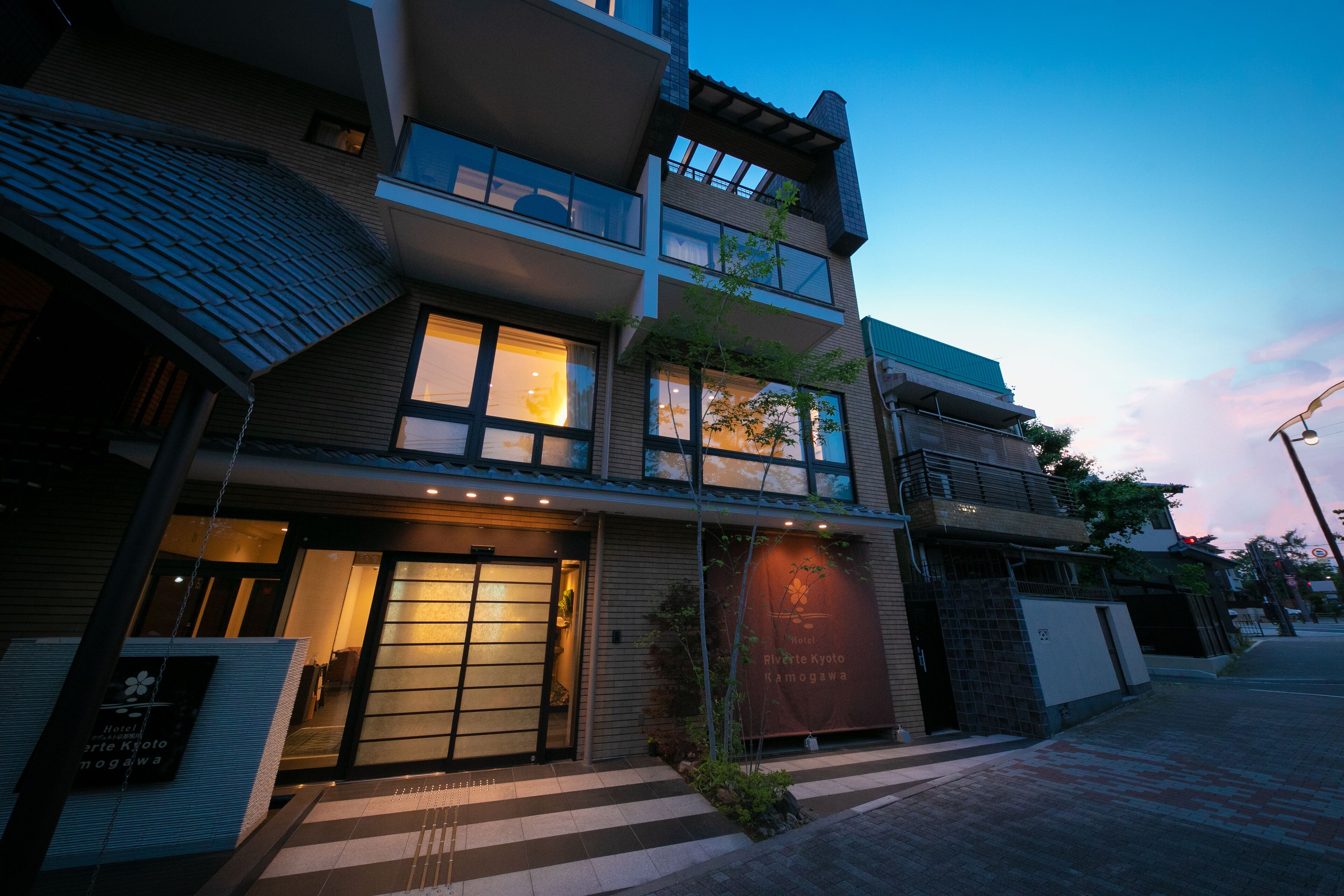 Un hotel a più piani con un ingresso dall'aspetto tradizionale, ampie finestre e un cartello che indica che si tratta dell'Hotel Riverside Kyoto.