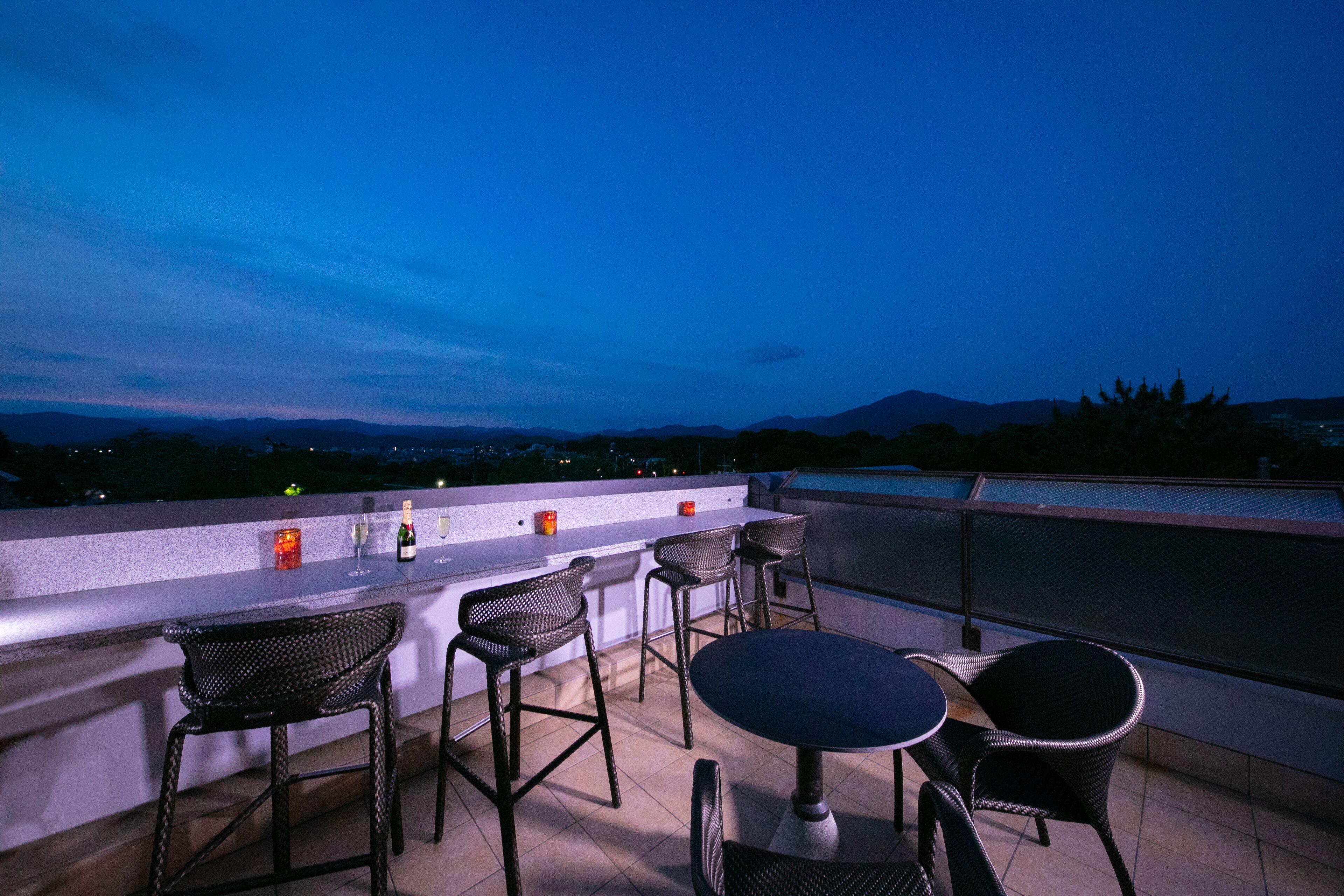 A rooftop bar with wicker furniture and a bar counter.