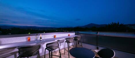 A rooftop bar with wicker furniture and a bar counter.