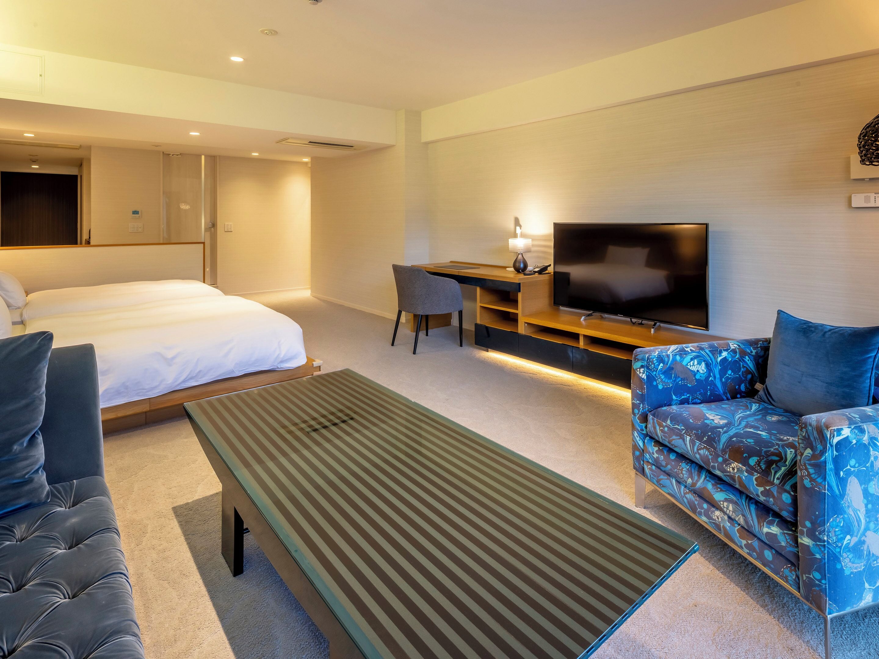A hotel room with a bed, a sofa, a TV, and a desk.