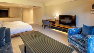 A hotel room with a bed, a sofa, a TV, and a desk.