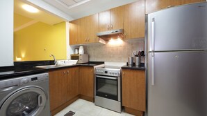 Een moderne keuken met roestvrijstalen apparatuur, houten keukenkastjes en een geel accentmuur.