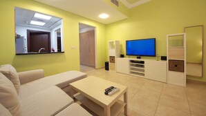 Een moderne woonkamer met een bank, een salontafel, een televisie en een inbouwmeubel.