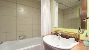Een badkamer met een badkuip, een wastafel, een spiegel en een handdoekhouder.