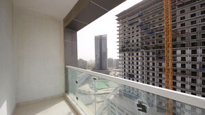 A balcony with a glass railing overlooking a construction site and high-rise buildings. - Signature Holiday Home - Red Residence (Dubai)