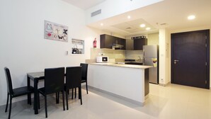A compact kitchen with a dining area, featuring a microwave, refrigerator, and a small island. - Signature Holiday Home - Red Residence (Dubai)
