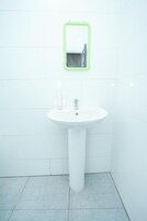Un baño con un lavamanos blanco, un espejo con marco verde y un inodoro blanco.