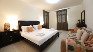 A bedroom with a bed, a nightstand, a dresser, a sofa, and a mirror.
