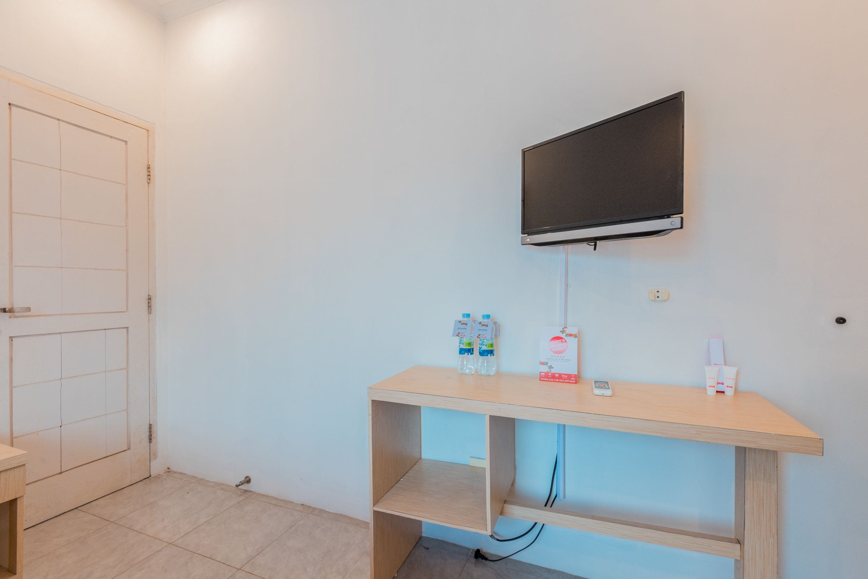 A room with a wooden desk, a mounted TV, and a door.