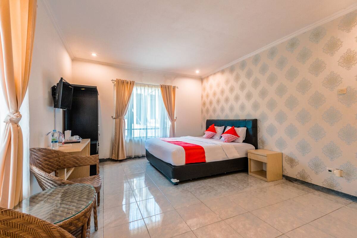 A hotel room with a bed, a desk, a chair, and a TV.