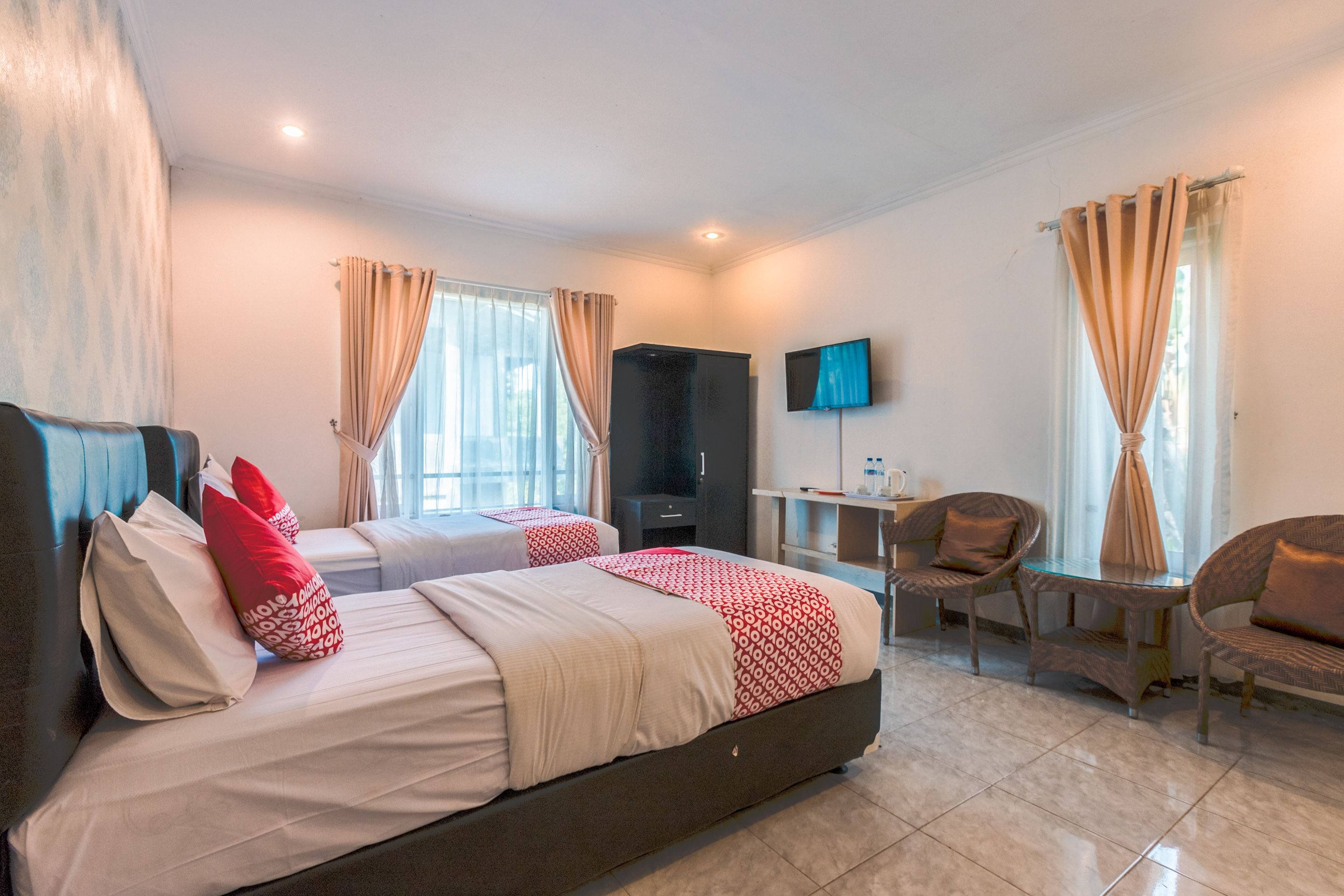 A hotel room with a large bed, two bedside tables, a TV, and a seating area with chairs.