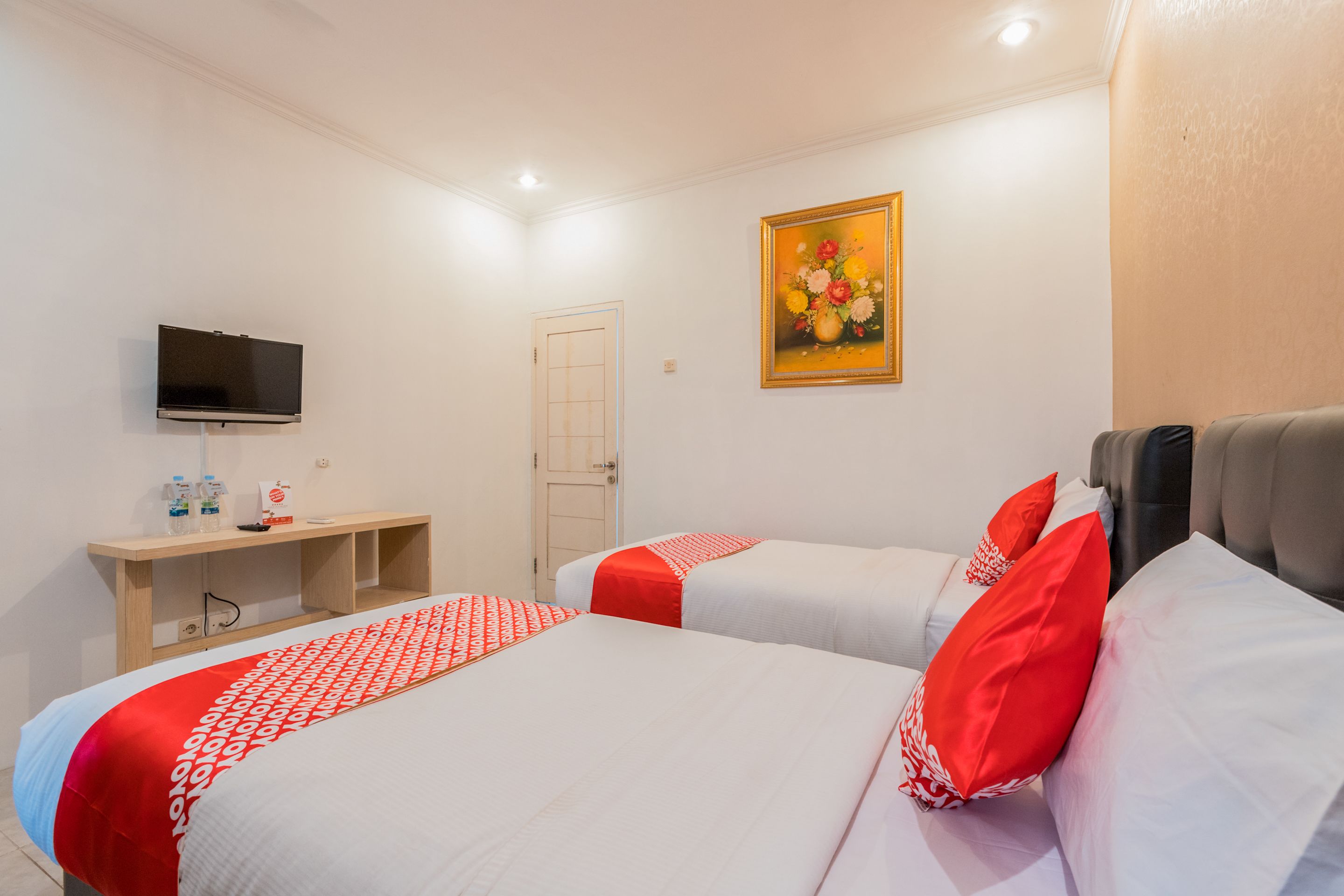 Habitación de hotel con dos camas, televisión, escritorio y silla, y una puerta.