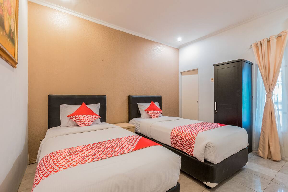 A hotel room with two beds, each with a patterned bedspread and pillows, a wardrobe, and a door.