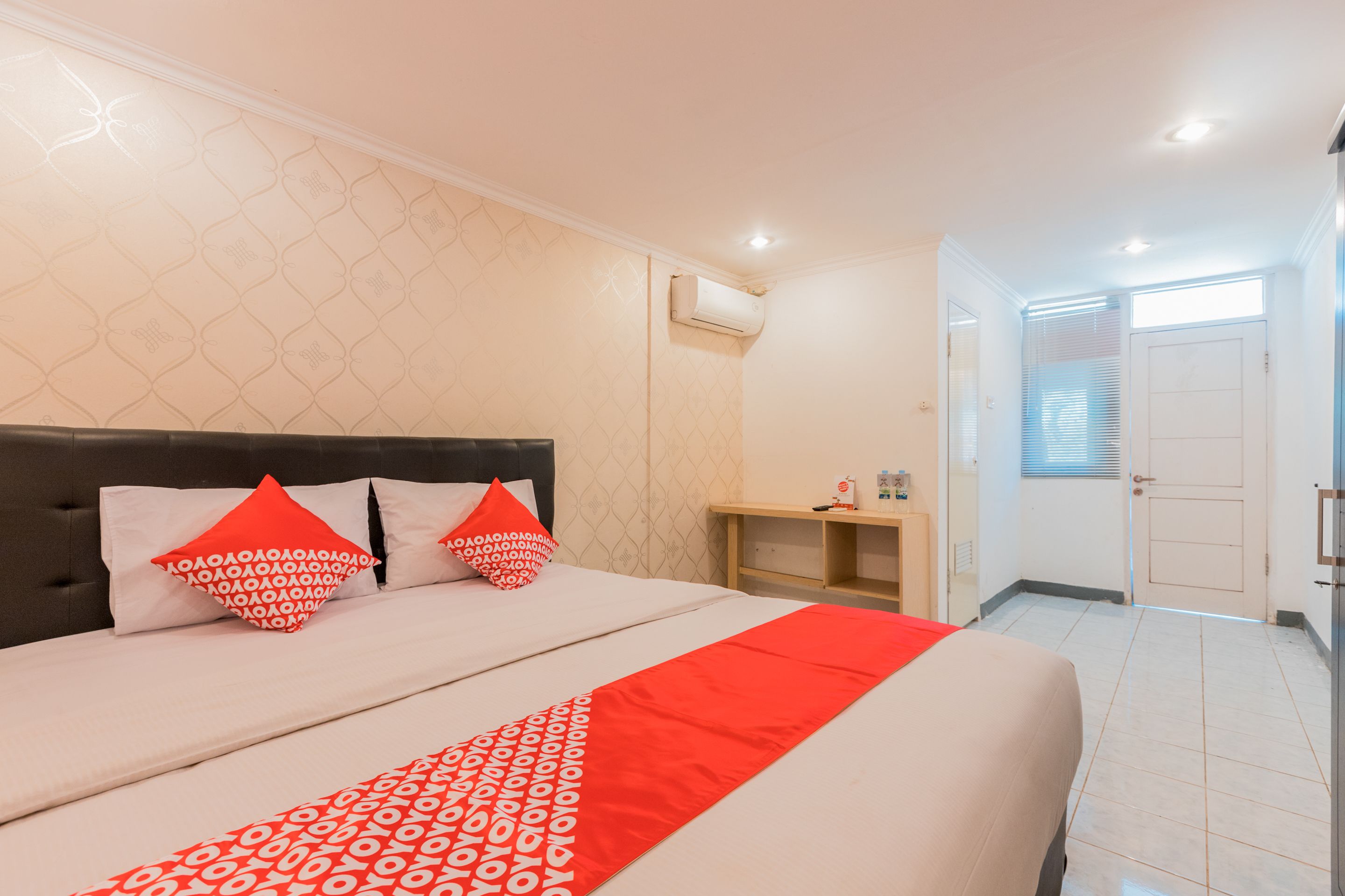 Una habitación de hotel ordenada con cama, almohadas, mesita de noche y armario.
