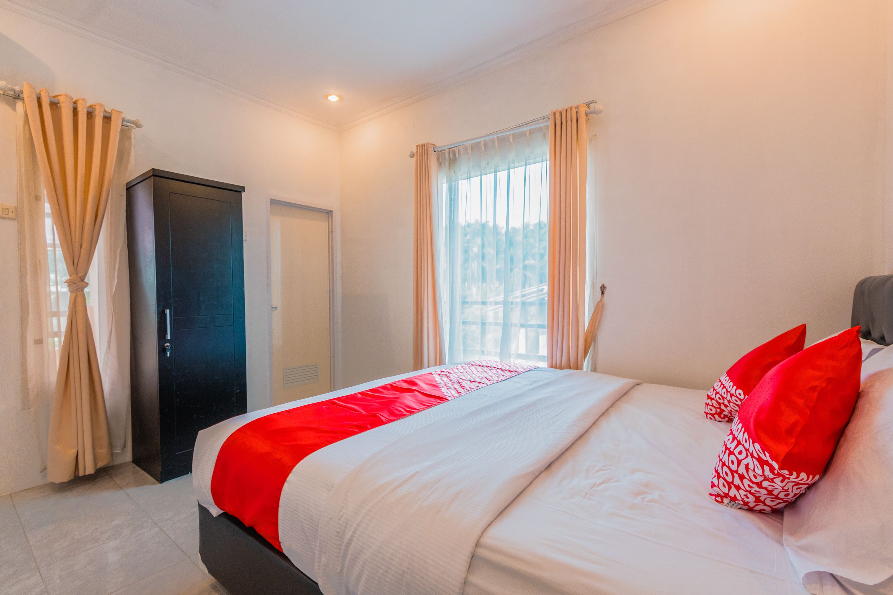 A hotel room with a bed, a door, and a window with curtains.