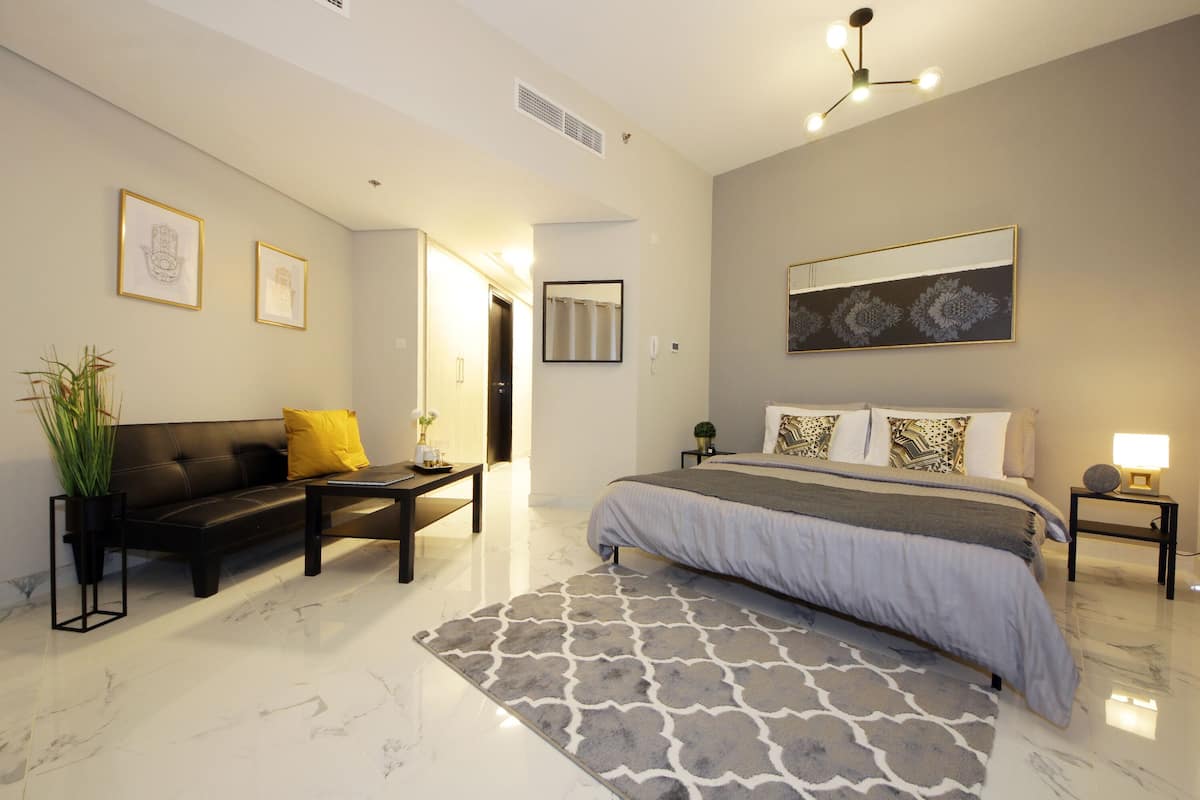 A modern bedroom with a large bed, a sofa, a coffee table, and a small side table.