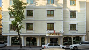 A multi-story hotel with a classical facade, featuring a central entrance with columns, multiple windows, and a visible flag. - Neccar Otel (Antakya)