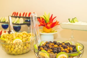 Un buffet proposant une variété de plats, notamment des olives, des fruits, et agrémenté d’un centre de table décoratif.