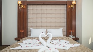 A hotel room with a large bed, a wooden headboard, two bedside lamps, and a telephone on the nightstand. - Neccar Otel (Antakya)