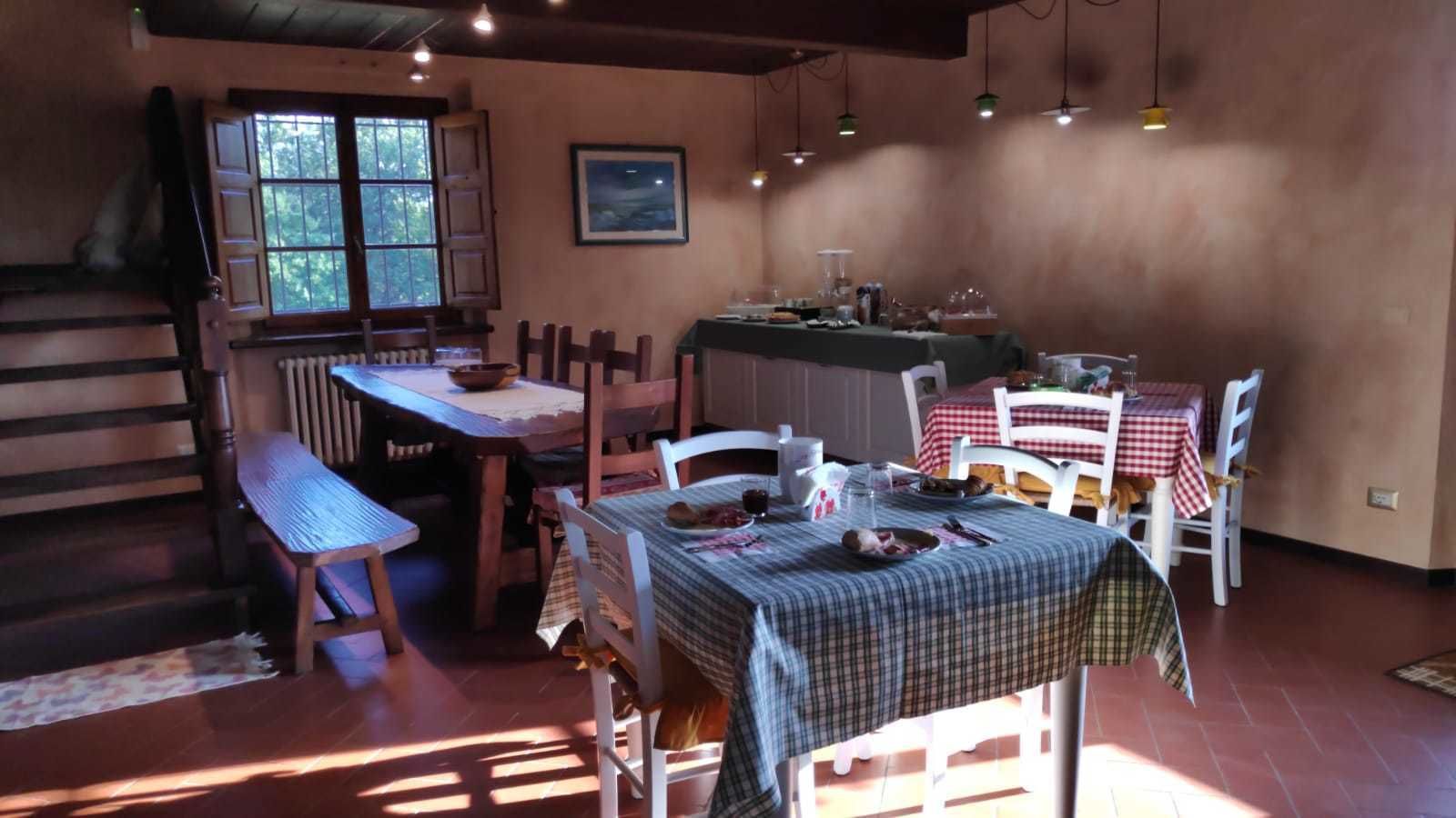 A rustic dining area with wooden furniture, a large table covered with a checkered tablecloth, and a window providing natural light.
