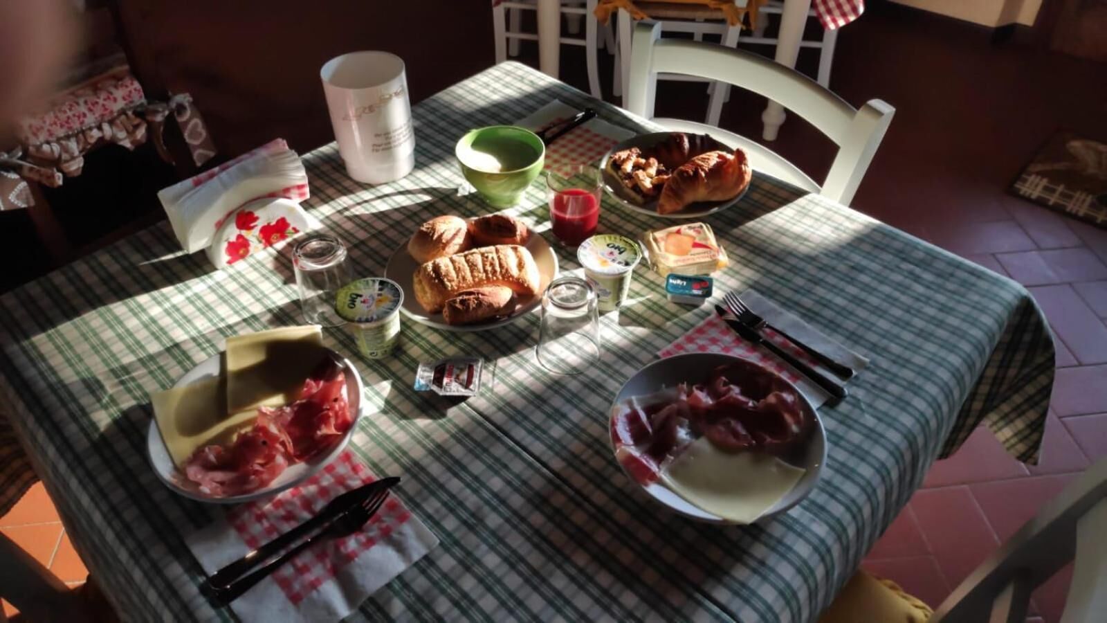 A table set with breakfast items including croissants, cheese, and fruit.