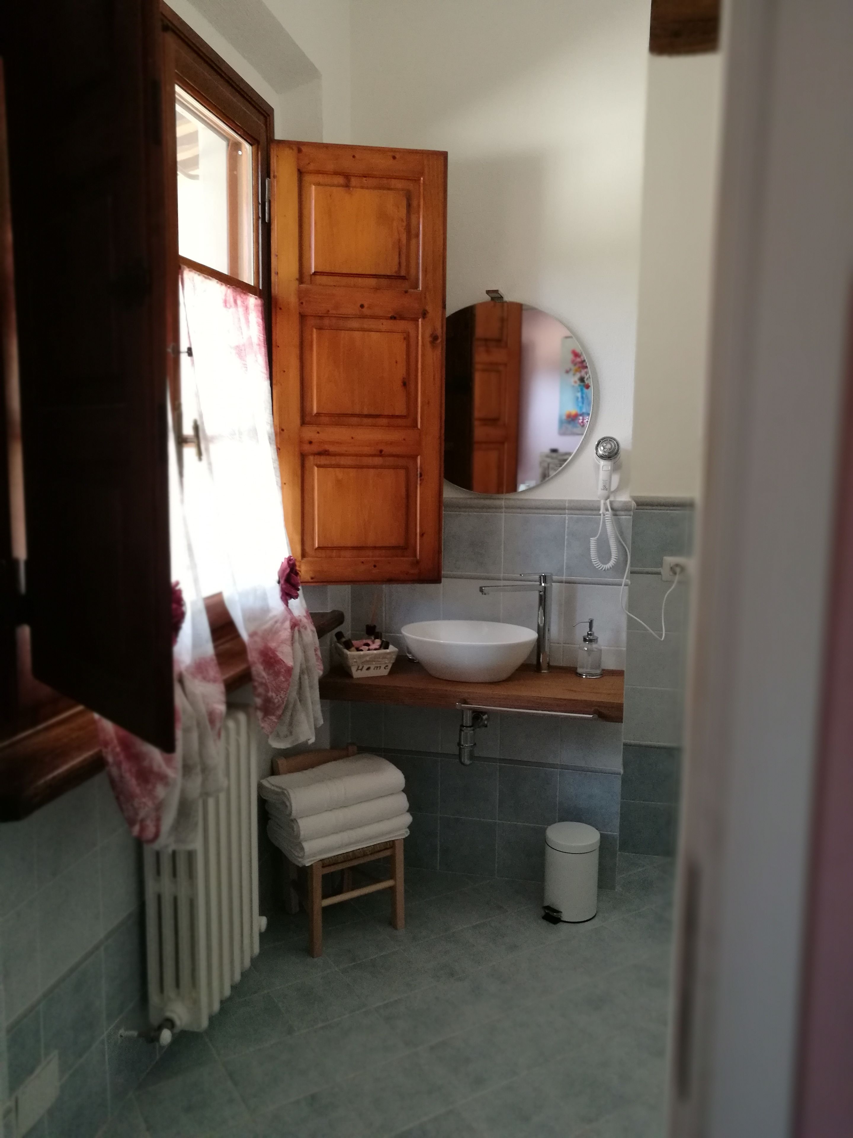 A small bathroom with a wooden cabinet, a white sink, a mirror, and a radiator.