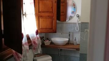 A small bathroom with a wooden cabinet, a white sink, a mirror, and a radiator.