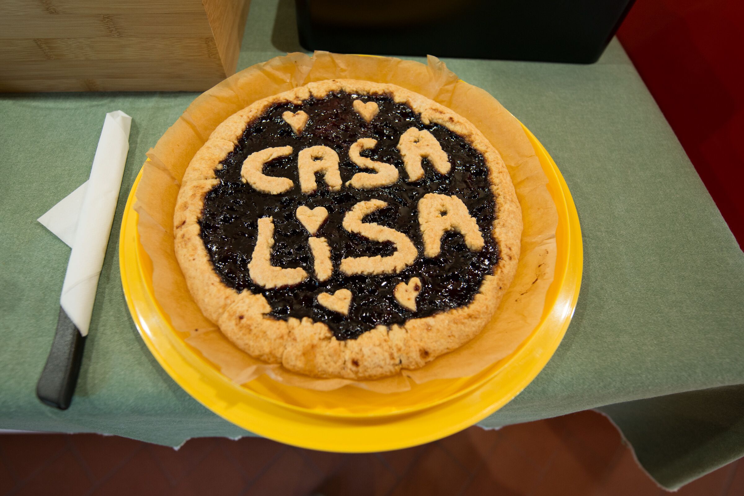A pie with "CASA LISA" written on it, placed on a yellow plate on a table.