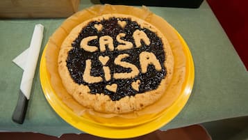 A pie with "CASA LISA" written on it, placed on a yellow plate on a table.