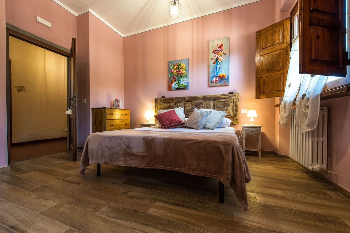 Un dormitorio con una cama de madera, una mesita de noche con lámpara, un aparador y un radiador.