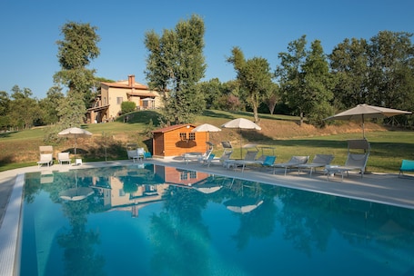 Una piscina al aire libre, sombrillas, sillones reclinables de piscina