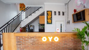 Un comptoir d’accueil avec un mur en briques et le nom « OYO » illuminé au-dessus.