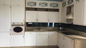 A kitchen with white cabinets, a built-in oven, and a sink. - Black Horse (Prešov)