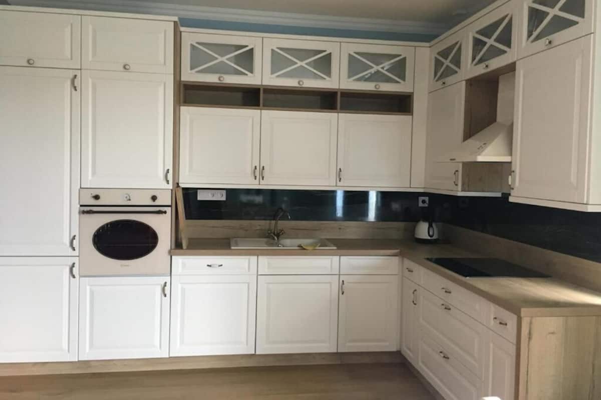 A kitchen with white cabinets, a built-in oven, and a sink.