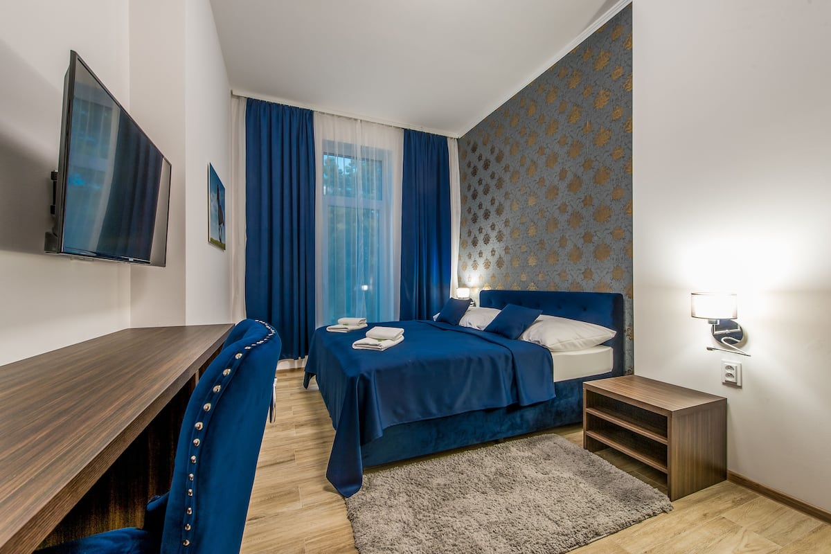 A modern bedroom with a bed, a desk, and a TV.