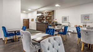 A modern dining area with a bar, blue and grey upholstered chairs, and a wooden bar counter. - Black Horse (Prešov)