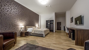 A modern bedroom with a large bed, a desk, and a seating area. - Black Horse (Prešov)