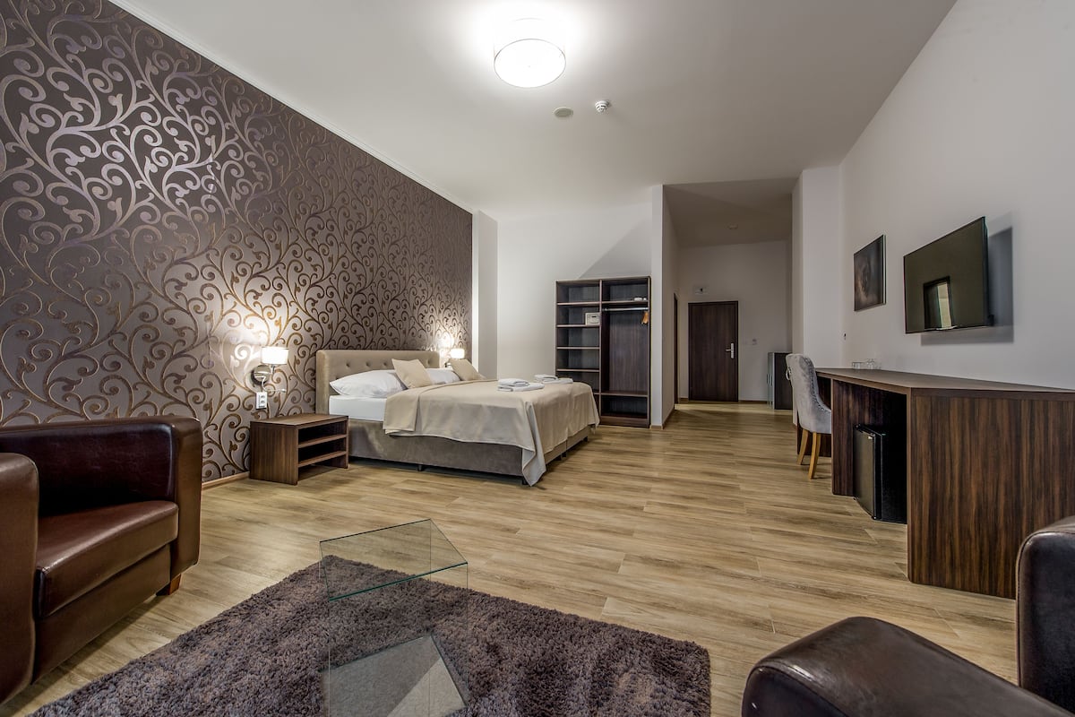 A modern bedroom with a large bed, a desk, and a seating area.