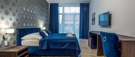 A bedroom with a bed, bedside tables, a desk, a chair, and a TV on the wall.