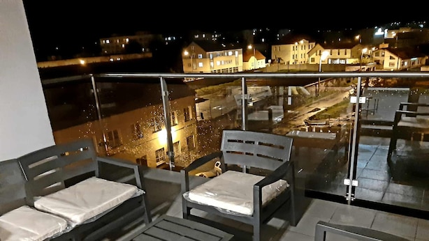A balcony with two grey chairs and a table, overlooking a lit-up residential area at night. - Black Horse (Prešov)