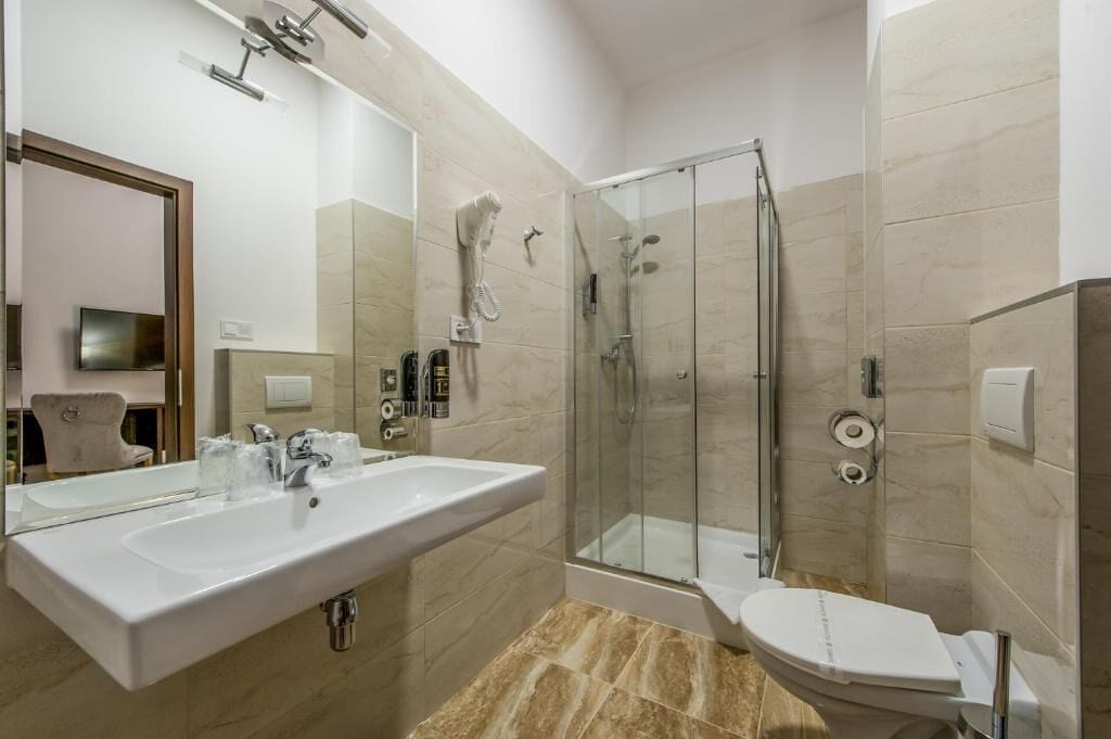 Un baño moderno con un lavamanos grande, una ducha con mampara de vidrio y un inodoro.