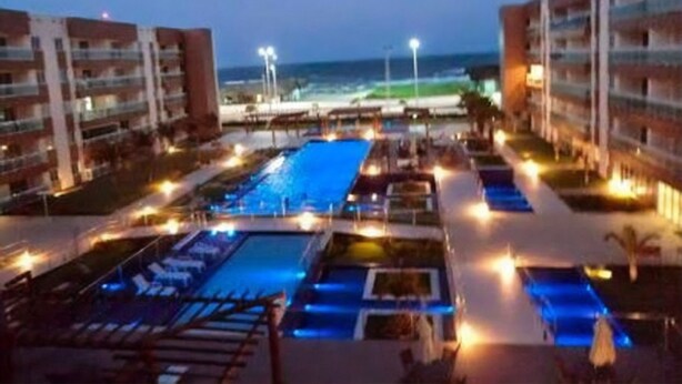 Ein Resort mit mehreren Schwimmbecken, Blick auf den Strand und gut beleuchteten Wegen.