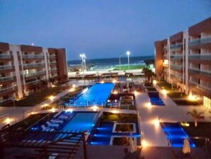 A resort with multiple swimming pools, a beach view, and well-lit pathways. - S Flats Mota (Fortaleza)