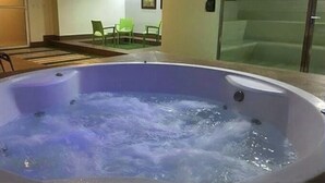 Ein Whirlpool mit Glasverkleidung, eine Sitzecke mit Stühlen und ein gerahmtes Bild an der Wand.