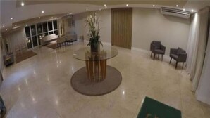 Eine geräumige Lobby mit einem Glastisch, einer Topfpflanze und einem Logo auf dem Boden.