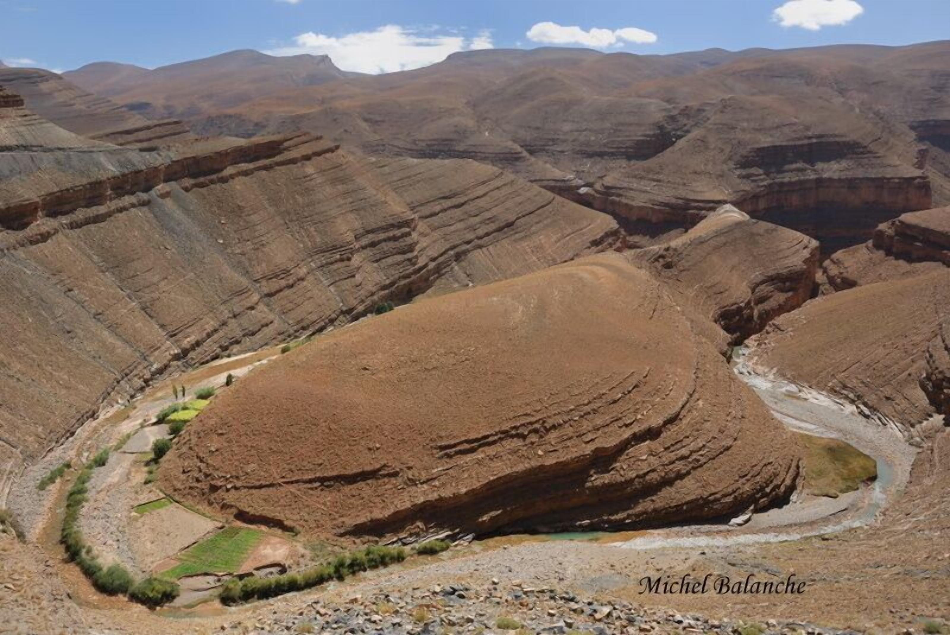 Un paisaje cañonero agreste con campos en terrazas y un río serpenteante.