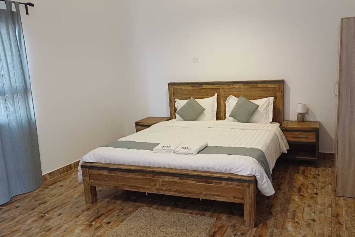A bedroom with a wooden bed, two nightstands, a wooden wardrobe, and a grey curtain.