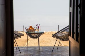 A patio with two chairs and a table with a fruit basket and flowers. - Hotel Hojari - Jabal Samhan, Salalah (Mirbat)