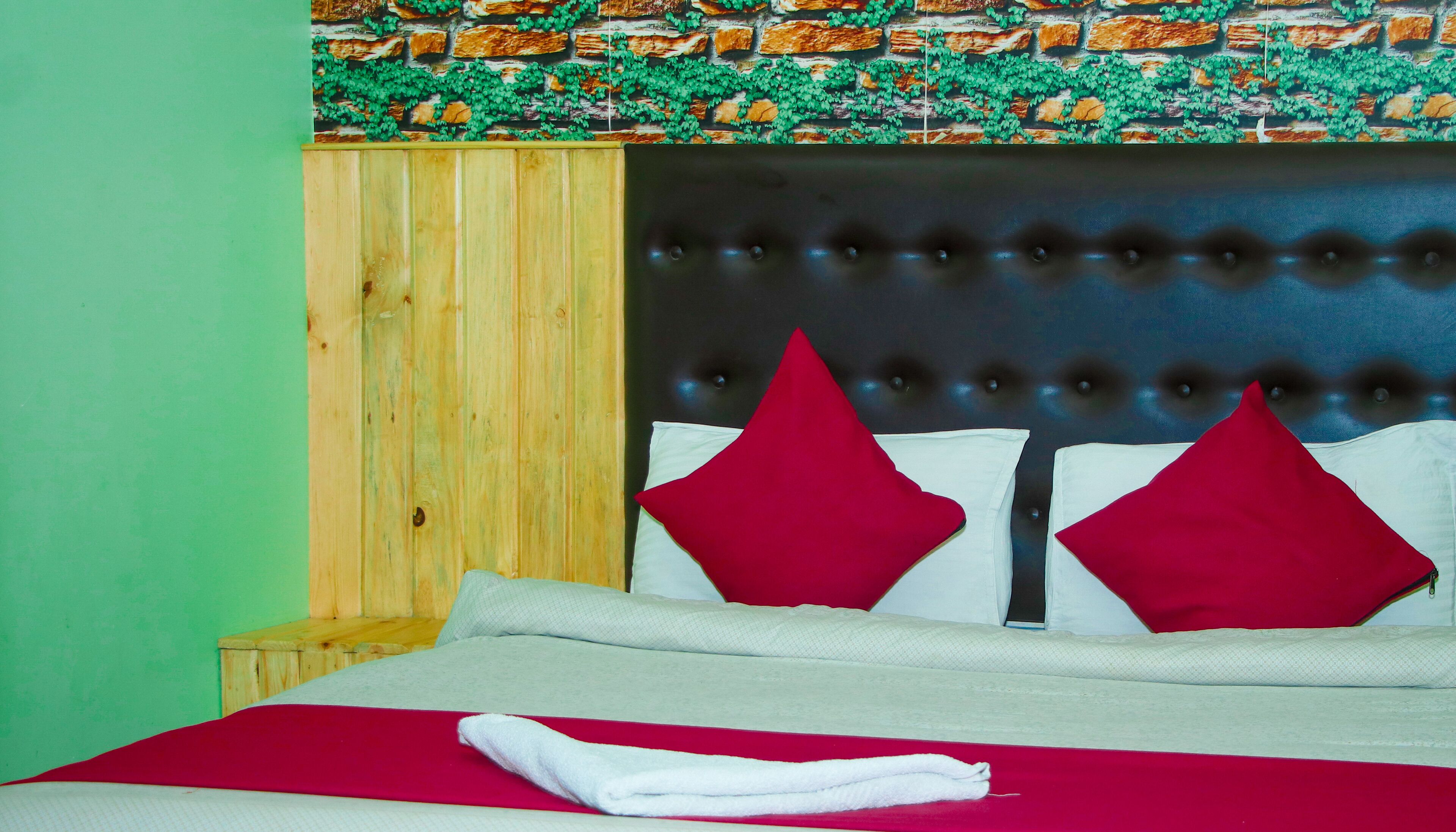 A bed with a wooden headboard, red and white pillows, and a red blanket.