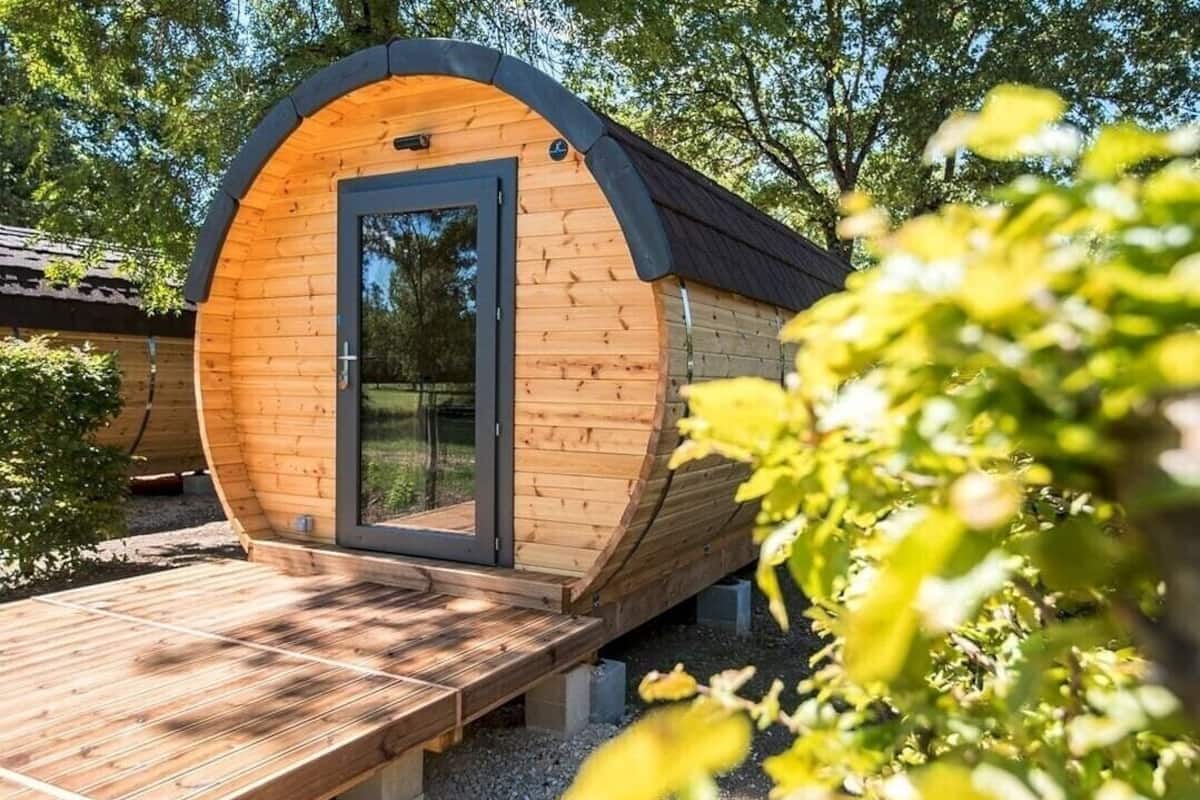 A wooden cabin with a curved roof, a door, and a wooden deck.